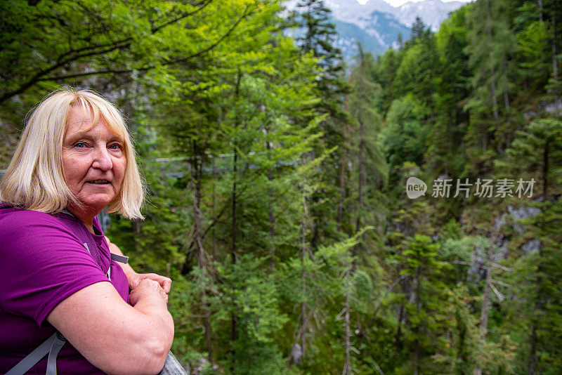 在奥地利阿尔卑斯山脉的Leutascher Geisterklamm，女性徒步旅行者在桥上俯瞰峡谷